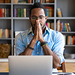 Photo of man at desk thinking or praying