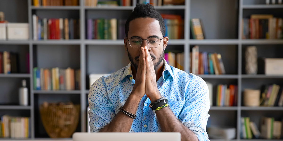 Photo of man at desk thinking or praying